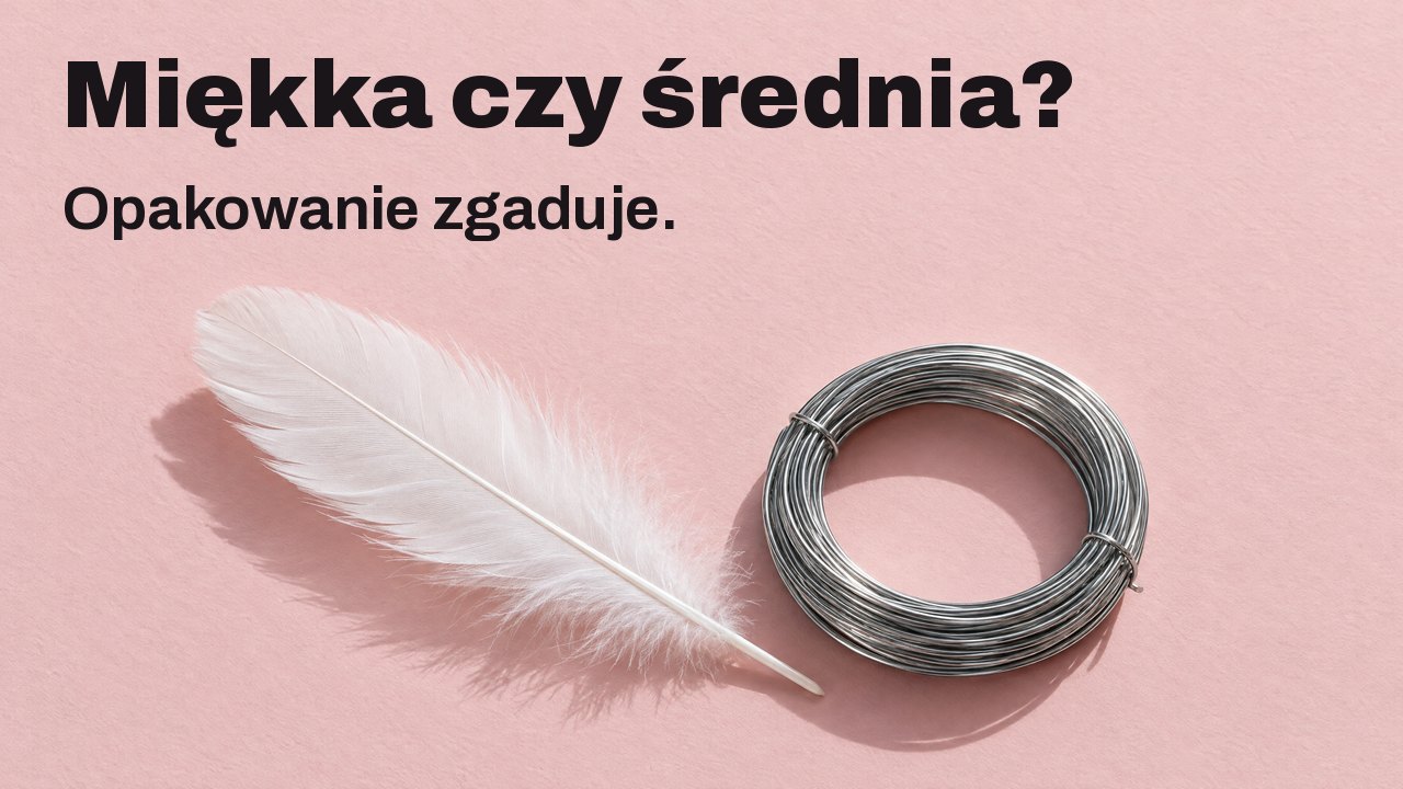 Miękka czy średnia? Opakowanie zgaduje. Z góry: miękkie białe pióro obok ciasnego zwoju sztywnego stalowego drutu na bladoróżowym papierze.