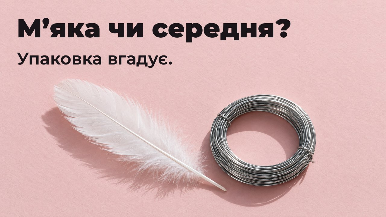 М’яка чи середня? Упаковка вгадує. Вигляд згори: м’яке біле перо поруч із тугим мотком жорсткого сталевого дроту на блідо рожевому папері.