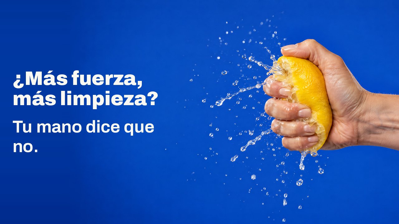 ¿Más fuerza, más limpieza? Tu mano dice que no. Una mano exprime un limón con tanta fuerza que el zumo estalla en una lluvia congelada, sobre azul cobalto.