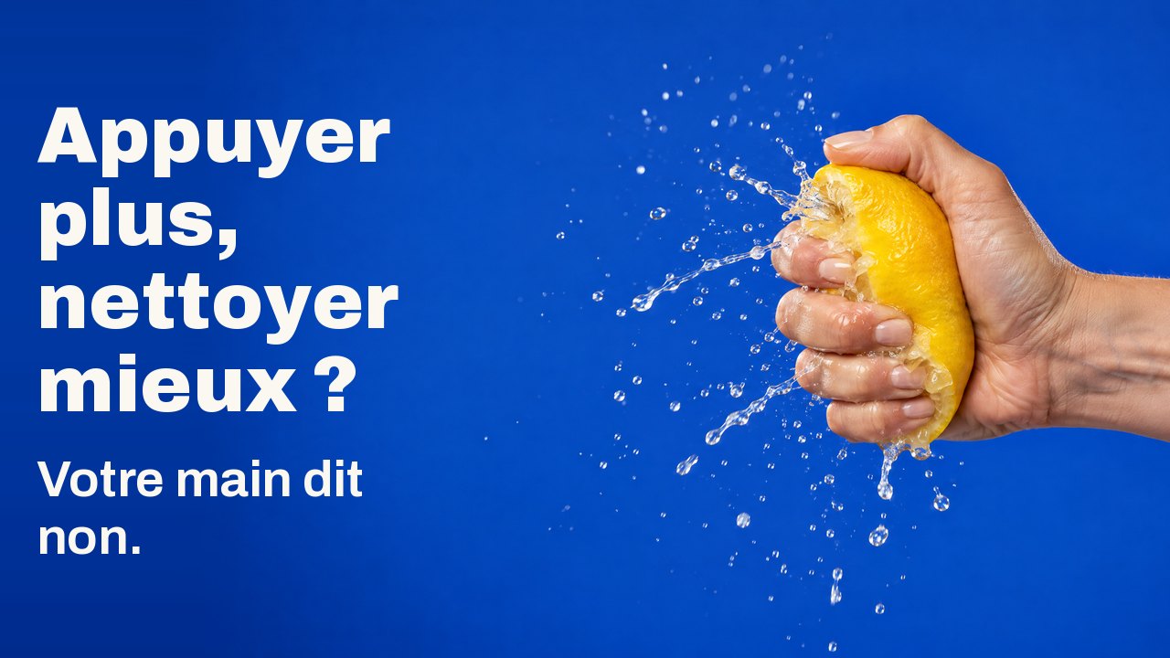 Appuyer plus, nettoyer mieux ? Votre main dit non. Une main presse un citron si fort que le jus jaillit en gerbe figée, sur bleu cobalt.