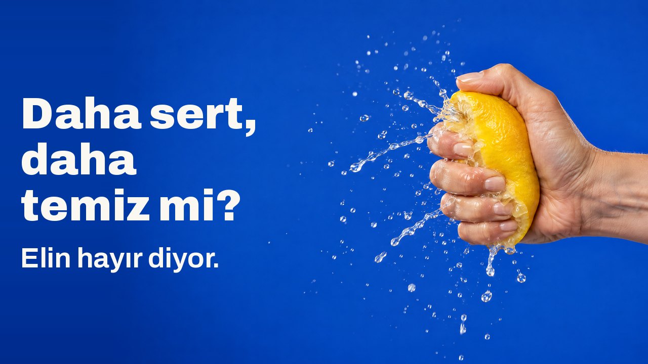 Daha sert, daha temiz mi? Elin hayır diyor. Bir el limonu öyle sıkıyor ki suyu donmuş bir sprey halinde fışkırıyor, kobalt mavisi fonda.