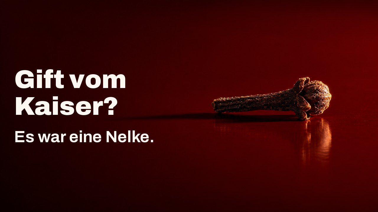Gift vom Kaiser? Es war eine Nelke. Eine einzelne dunkle Nelkenknospe liegt wie ein kleiner Eisennagel auf einem glänzenden zinnoberroten Lacktablett, hart von einer Seite beleuchtet, ihr langer Schatten zieht sich über den Lack.
