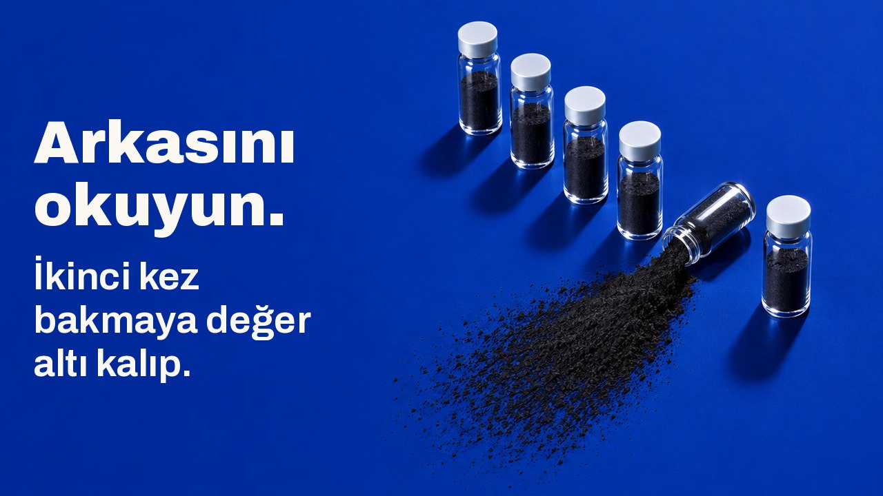 Arkasını okuyun. İkinci kez bakmaya değer altı kalıp. Koyu kobalt mavisi bir yüzeyde yukarıdan görünüm: altı küçük cam şişe yan yana duruyor, biri devrilmiş ve yelpaze gibi siyah kömür tozu saçmış.
