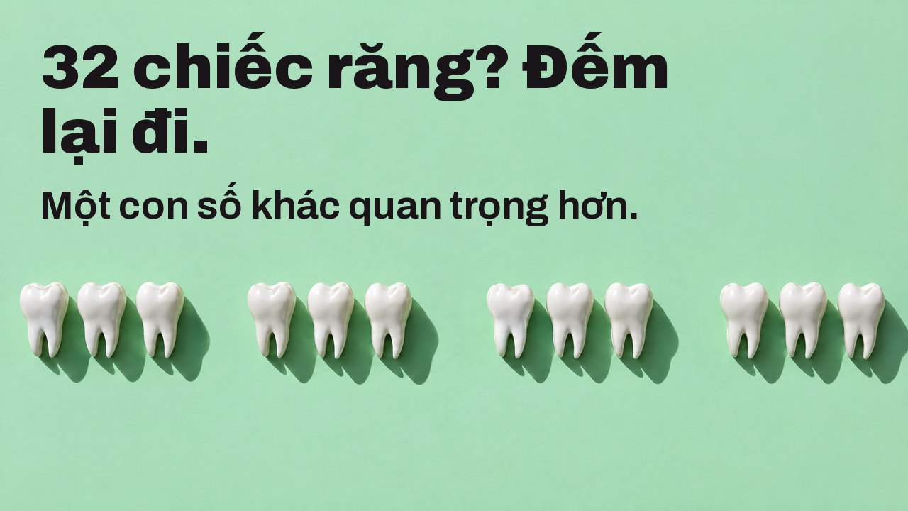 32 chiếc răng? Đếm lại đi. Một con số khác quan trọng hơn. Nhìn từ trên: một hàng tượng răng trắng trên nền xanh bạc hà, có khoảng trống ở chỗ thiếu răng.