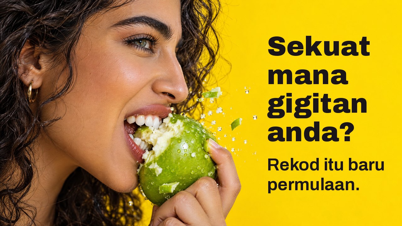 Sekuat mana gigitan anda? Rekod itu baru permulaan. Gambar dekat sisi seorang wanita menggigit kuat epal hijau rangup, serpihan berterbangan, berlatarkan kuning terang.