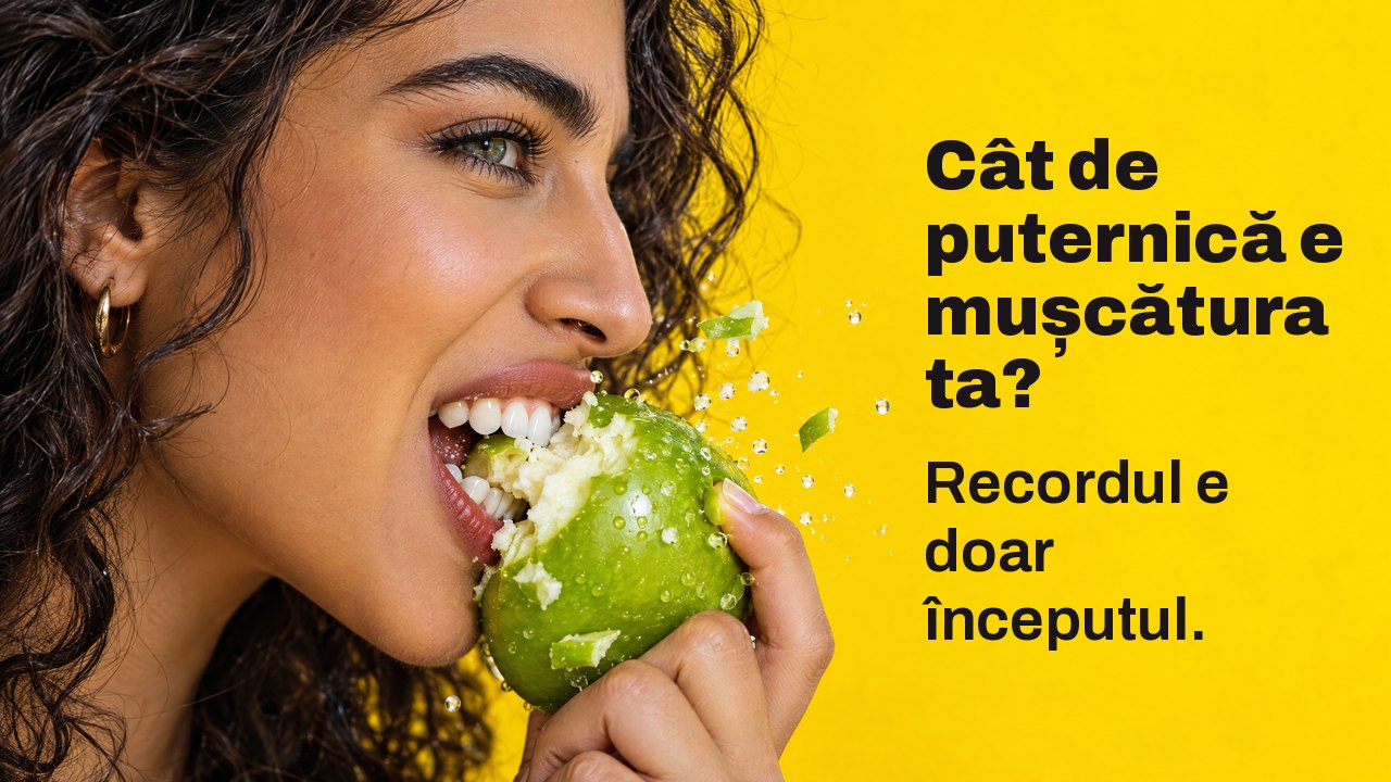 Cât de puternică e mușcătura ta? Recordul e doar începutul. Prim plan din profil al unei femei care mușcă puternic un măr verde crocant, cu bucăți zburând, pe galben intens.