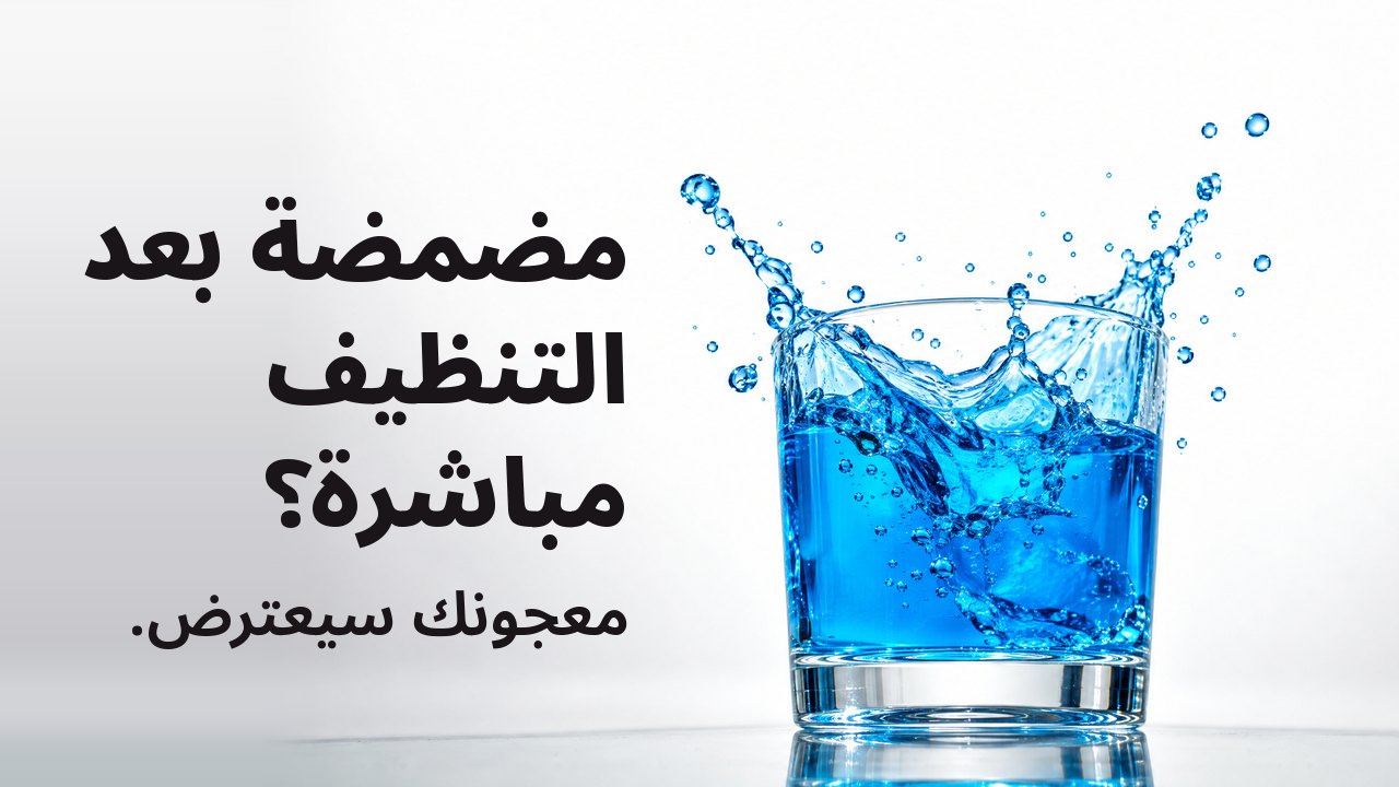 مضمضة بعد التنظيف مباشرة؟ معجونك سيعترض. غسول فم أزرق زاهٍ يتطاير من كأس شفافة متجمدًا في الهواء، على خلفية استوديو بيضاء.