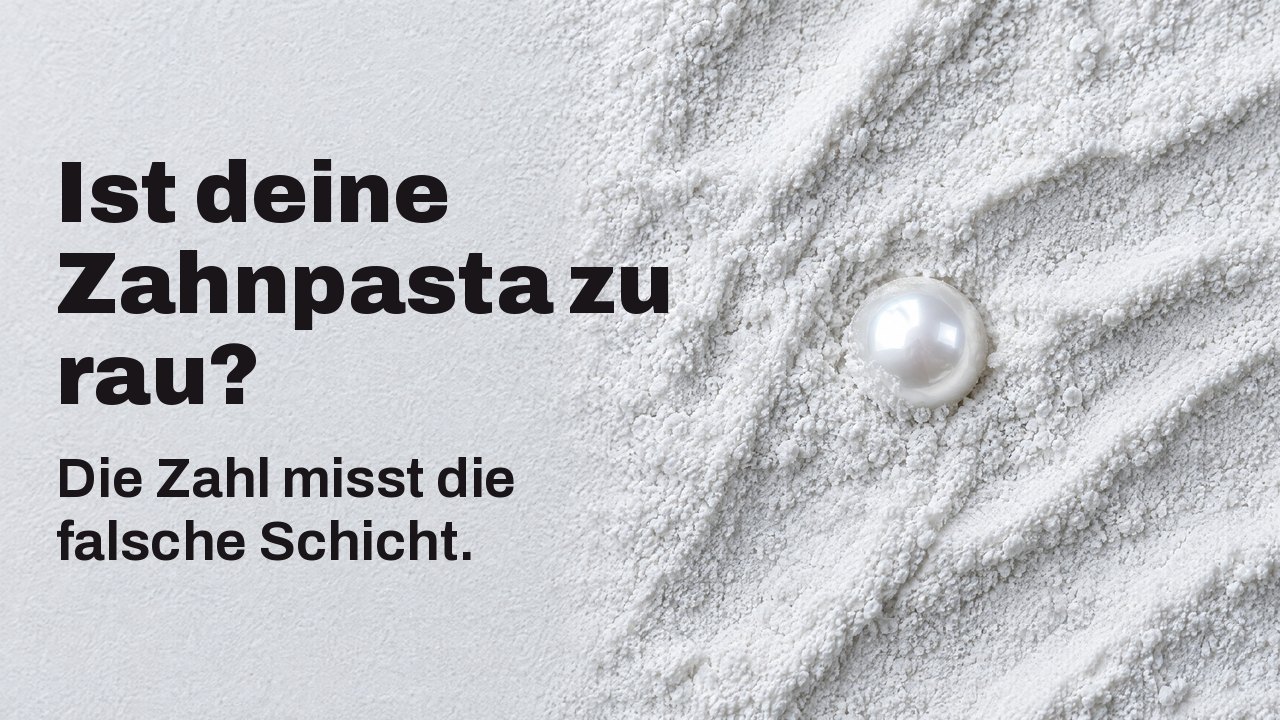 Ist deine Zahnpasta zu rau? Die Zahl misst die falsche Schicht. Von oben: eine einzelne glänzende Perle, halb in feinem weißem Schleifpulver vergraben.