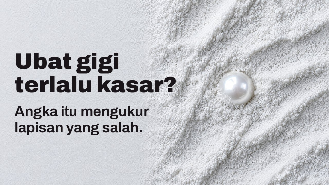 Ubat gigi terlalu kasar? Angka itu mengukur lapisan yang salah. Dari atas: sebutir mutiara berkilat separuh terbenam dalam serbuk pelelas putih halus.