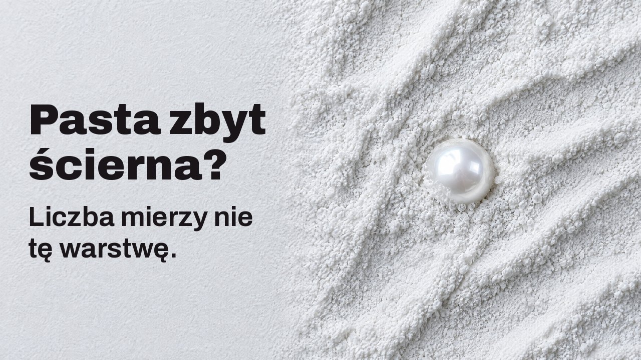 Pasta zbyt ścierna? Liczba mierzy nie tę warstwę. Z góry: pojedyncza lśniąca perła do połowy zagłębiona w drobnym białym proszku ściernym.