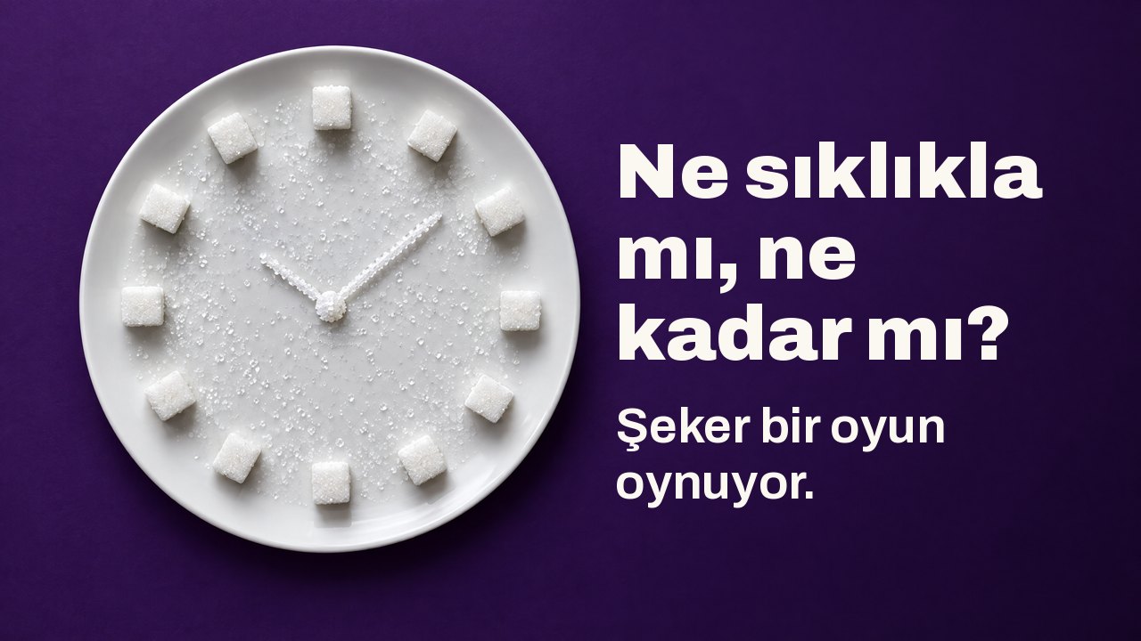 Ne sıklıkla mı, ne kadar mı? Şeker bir oyun oynuyor. Yukarıdan: beyaz tabakta saat kadranı gibi dizilmiş küp şekerler ve kristaller, koyu mor fonda.