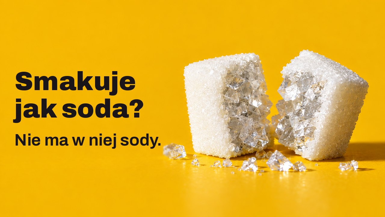 Smakuje jak soda? Nie ma w niej sody. Bardzo bliskie ujęcie z wysokości stołu na ciepłym, szafranowym tle: biała kostka cukru przełamana na pół, a w środku nie cukier, tylko duże, szkliste kryształy soli.